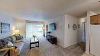 Located along US-131 S in Plainwell, Michigan, this single-floor residence offers a thoughtfully laid-out living space with a comfortable and functional design throughout. The living room serves as the centerpiece of the unit, featuring plush carpet flooring, neutral-toned walls, and a large sliding glass door with vertical blinds that fills the room with natural light and provides access to the outdoors. The open, airy atmosphere makes it an ideal space for both relaxing and entertaining. Adjacent to the living room, the dining area features tile flooring, a ceiling fan with light fixture, and direct access to the entry door, creating a welcoming transition between spaces. The kitchen is efficiently designed with warm oak cabinetry, light countertops, tile flooring, and includes essential appliances such as a range and dishwasher, offering ample storage and workspace. The unit includes two carpeted bedrooms, each featuring windows with blinds that allow for natural light and privacy. Both rooms offer a calm, restful ambiance with neutral walls and sufficient space for furnishings. The full bathroom is finished with white tile, a navy accent tile border, a single-sink vanity with oak cabinetry, and a shower-tub combination, providing clean and practical functionality.