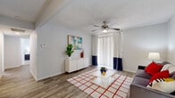 This single-floor, 3-bedroom, 2-bathroom residence offers a thoughtfully organized layout that maximizes every inch of its living space. The living room serves as a welcoming central hub, featuring wood-look flooring, a textured ceiling with an overhead ceiling fan, and a large sliding glass door dressed in two-tone curtains that invites natural light and provides outdoor access. The kitchen is designed for functionality, boasting dark charcoal cabinetry, white countertops, a stainless steel sink, and black appliances including a range and refrigerator, all set atop matching wood-look flooring. Both bathrooms are finished with clean white tile surrounds and tub-shower combinations, complemented by sleek cabinetry with modern hardware. The primary bedroom offers a comfortable, carpeted retreat with a ceiling fan and a generously sized walk-in closet equipped with dual hanging rods and built-in shelving. The two additional bedrooms are equally cozy, each with plush carpet and ceiling fans. A dedicated hallway and closet complete the layout, contributing to the overall efficient flow of the home. Neutral tones throughout create a clean, versatile backdrop suited to a variety of styles.