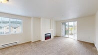 This single-floor, 2-bedroom, 2-bathroom residence offers a practical and comfortable layout designed to maximize livability. The inviting living room serves as the heart of the home, centered around a built-in fireplace framed by a classic white mantel. Plush wall-to-wall carpeting runs throughout, adding warmth underfoot, while a sliding glass door opens to a private balcony with outdoor views, filling the space with natural light.

The primary bedroom is generously sized, offering ample room for furnishings, and features a dedicated closet for storage. Its en-suite bathroom is well-equipped with a double-sink vanity set in warm wood cabinetry, a large mirror, tile flooring, and a full soaking tub. The second bedroom is bright and carpeted, also offering a closet with sliding doors and a ceiling-mounted light fixture.

A hallway connects the main living areas to the private quarters, maintaining a logical and efficient flow throughout. The dedicated laundry room includes a full-size washer and dryer with wire shelving above for added utility. Tile flooring in the wet areas and light, neutral wall tones throughout create a clean, cohesive aesthetic. The space is completed by a well-organized closet and a second full bathroom, making this a thoroughly functional and comfortable home.