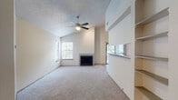 Located at 800 E Ash Lane in Euless, Texas, this single-floor residence offers a well-organized layout designed for comfortable living. The spacious living room is a standout feature, boasting soaring vaulted ceilings, a ceiling fan with light kit, and a tile-surround fireplace that serves as the room's focal point. Soft carpeting runs throughout, and multiple windows allow natural light to fill the space. A built-in shelving unit adds functional storage and display space along one wall, while a pass-through window connects the living area to the kitchen. The galley-style kitchen is efficiently designed, featuring white cabinetry, granite-look countertops, a mosaic tile backsplash, wood-look flooring, track lighting, and a full suite of black appliances including a refrigerator, range, and built-in microwave. The bedrooms are generously sized, each with plush carpeting, ceiling fans, and ample natural light from windows with blinds. The bathrooms are clean and functional, each equipped with a full tub-shower combination, vanity with storage, and wood-look flooring. Throughout the home, a neutral color palette and textured ceilings contribute to a bright, cohesive ambiance suited for a variety of lifestyles.