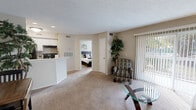 This thoughtfully laid-out single-floor residence features 1 bedroom and 2 bathrooms within a compact, efficient footprint. The open-concept living room serves as the heart of the home, finished with plush wall-to-wall carpeting and anchored by a sliding glass door dressed in vertical blinds that invites natural light and provides access to an outdoor area. The space flows seamlessly into the kitchen, which is positioned behind a peninsula-style breakfast bar. The kitchen features white cabinetry, light countertops, tile flooring, and black appliances including a refrigerator and electric range, offering practical functionality in a clean, organized layout. The bedroom is a comfortable retreat with a window that allows natural light to filter in, textured ceiling, soft carpeting, and direct access to a dedicated walk-in closet equipped with built-in shelving. Two full bathrooms serve the unit, one of which includes a tiled shower-tub combination with a curtain enclosure. Throughout the residence, neutral warm-toned walls, recessed lighting, and consistent carpeting create a cohesive and inviting ambiance, making this a practical and comfortable living space.