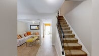 Located at 8800 Howard Hills Dr in Savage, MD, this two-story home offers 2 bedrooms and 2 bathrooms thoughtfully distributed across two floors. The main level houses the living and dining areas along with the kitchen, while the upper level is dedicated to the bedrooms and bathrooms.

The kitchen features light maple cabinetry, dark granite-style countertops, tile flooring, and full white appliances including a refrigerator, dishwasher, and electric range — all set against sage green walls. The dining area, painted in a soft green, accommodates a cozy dining set beneath a multi-bulb pendant light. The living area includes carpeted flooring and natural light from windows with outdoor views of lush greenery.

Both bedrooms are carpeted and feature warm earth-tone accent walls. The primary bedroom is generously sized, with natural light from large windows. The second bedroom is equally well-appointed. A full bathroom with tile flooring, a tub-shower combo, and bold horizontal striped walls completes the upper level.

Additional flex space is visible, suitable for a home office or study, also carpeted and naturally lit. Throughout the home, consistent warm tones, carpet flooring, and framed artwork contribute to a cohesive and inviting ambiance.