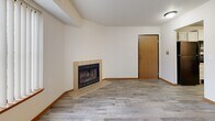 Located at 1056 Yellow Brick Rd in Chaska, MN, this well-appointed one-bedroom, one-bathroom unit offers a comfortable and functional single-floor layout. The open living room is a standout space, featuring light wood-look flooring, a tile-surround fireplace, a large picture window, and a private entry door that fills the room with natural light and outdoor views of the surrounding trees. A textured ceiling and warm wood baseboards add classic character throughout.

The updated kitchen is thoughtfully designed with crisp white shaker-style cabinetry, light stone-look countertops, and a full suite of black appliances including a refrigerator, electric range with over-the-range microwave, and dishwasher. A stainless steel sink with a modern faucet completes this practical and attractive cooking space.

The generously sized bedroom offers plush carpeting, a large sliding-door closet, a window with natural light, and a textured ceiling, creating a quiet and comfortable retreat. The full bathroom is clean and well-finished, featuring a grey vanity with white countertop, lighted mirror, tiled flooring, a full soaking tub with shower, and grab bars for added accessibility. This unit combines practicality with inviting finishes throughout.