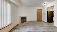 Located at 1056 Yellow Brick Rd in Chaska, MN, this well-appointed one-bedroom, one-bathroom unit offers a comfortable and functional single-floor layout. The open living room is a standout space, featuring light wood-look flooring, a tile-surround fireplace, a large picture window, and a private entry door that fills the room with natural light and outdoor views of the surrounding trees. A textured ceiling and warm wood baseboards add classic character throughout.

The updated kitchen is thoughtfully designed with crisp white shaker-style cabinetry, light stone-look countertops, and a full suite of black appliances including a refrigerator, electric range with over-the-range microwave, and dishwasher. A stainless steel sink with a modern faucet completes this practical and attractive cooking space.

The generously sized bedroom offers plush carpeting, a large sliding-door closet, a window with natural light, and a textured ceiling, creating a quiet and comfortable retreat. The full bathroom is clean and well-finished, featuring a grey vanity with white countertop, lighted mirror, tiled flooring, a full soaking tub with shower, and grab bars for added accessibility. This unit combines practicality with inviting finishes throughout.