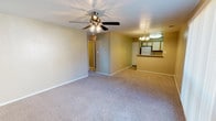 This single-story, two-bedroom, two-bathroom unit offers a practical and comfortable layout designed for everyday living. The open-concept living and dining area is finished with neutral-toned carpet and warm beige walls, creating a welcoming atmosphere. A ceiling fan with light kit overhead provides both comfort and illumination, while a large window with vertical blinds allows natural light to fill the space. The living area flows seamlessly toward a pass-through kitchen bar accented by a chandelier, making it ideal for casual dining or entertaining.

The kitchen is equipped with white appliances, including an electric range, built-in microwave, and refrigerator. Wood-toned cabinetry pairs with speckled countertops that extend to the bar overhang. A stainless steel double sink sits beneath ample counter space, and tile flooring adds durability to the area.

Both bedrooms are generously sized, carpeted, and feature ceiling fans with light kits. Each room benefits from natural light through windows with blinds. The primary bedroom includes a closet with bi-fold doors and an en-suite bath. Both bathrooms are finished with tile flooring, speckled vanity countertops, and a tub/shower combination, offering a clean, functional design throughout.
