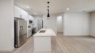 Located at 110 Frem Boustany Dr in Lafayette, Louisiana, this thoughtfully designed one-bedroom, one-bathroom residence offers a clean, contemporary aesthetic throughout its single-level layout. Light-toned luxury vinyl plank flooring runs continuously through the space, complementing the bright white walls and modern finishes.

The kitchen serves as the centerpiece of the open-concept living area, anchored by a generously sized island with a white quartz countertop and an undermount sink. Sleek white upper cabinetry contrasts with light gray lower cabinets, all equipped with matte black hardware. A patterned tile backsplash adds visual interest behind the stainless steel appliances, which include a French door refrigerator, gas range, and built-in microwave. Striking black pendant lights hang above the island, adding a modern design accent.

The bedroom is a comfortable, well-lit retreat featuring dual windows that invite natural light, a ceiling fan, and direct access to both a walk-in closet and the full bathroom. The bathroom is finished with a wide vanity, quartz countertop, and a tub-shower combination dressed in elegant marble-style tile surround.

A dedicated laundry room houses a full-size washer and dryer, adding practical convenience. The hallway connects all areas efficiently, making the layout feel intuitive and functional throughout.