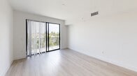 This thoughtfully designed 3-bedroom, 2-bathroom apartment at 103 W Camino Real offers a clean, contemporary aesthetic throughout. Light wood-tone flooring flows seamlessly across all rooms, complemented by crisp white walls that create a bright and airy atmosphere.

The open kitchen and living area serves as the heart of the home, featuring modern flat-panel cabinetry in a warm light wood finish, stainless steel appliances including a side-by-side refrigerator, electric range, over-the-range microwave, and dishwasher, all set against white countertops and a clean tile backsplash. Track lighting above adds both function and style.

The bedrooms are well-proportioned, with the primary bedroom offering a generous footprint. Each room features white walls, ceiling fans with light fixtures in select rooms, and windows with slatted blinds that invite natural light and outdoor views. Connecting hallways are clean and efficient, maintaining the home's cohesive flow.

Storage is well-addressed, with two closets outfitted with wire shelving systems, including a spacious walk-in closet ideal for the primary bedroom. The bathrooms are finished in a contemporary style — one features a large glass-enclosed walk-in shower with floor-to-ceiling tile, while the other includes a vanity with light wood cabinetry, a wide mirror, and a tall storage tower.