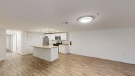 Located at 123 Creek Rd in Mount Laurel, NJ, this 2-bedroom, 2-bathroom unit offers a clean, modern aesthetic throughout its single-floor layout. Light wood-look flooring runs continuously across every room, creating a cohesive and bright atmosphere that is complemented by crisp white walls and white trim.

The open-concept living room and kitchen area serves as the heart of the unit. The living room is generously proportioned, with a multi-pane front window and entry door that allow natural light to fill the space. The kitchen is a standout feature, anchored by a large granite-topped island with an integrated sink and pendant lighting overhead. White shaker-style cabinetry lines the walls, and stainless steel appliances — including a gas range, over-the-range microwave, and full-size refrigerator — complete the modern, functional setup.

Both bedrooms are well-sized, bright, and feature the same light flooring with overhead lighting and windows providing natural light. Each room includes dedicated closet space. The primary bedroom is a comfortable size, suitable for a full bedroom suite.

The two bathrooms maintain the clean, white design language of the unit. One features a tub-shower combination with marble-style surround, while the other is a half-style bath — both include white vanity cabinetry and updated light fixtures.