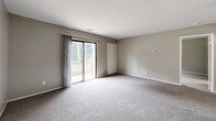 Located at 2400 Andrew Avenue in La Porte, Indiana, this single-floor home offers two bedrooms and one bathroom with a practical, functional layout. The interior is finished with neutral gray walls and wall-to-wall carpeting throughout the living and bedroom areas, creating a clean and cohesive aesthetic.

The spacious primary bedroom is a standout feature, offering generous room and a sliding glass door that opens directly to an outdoor deck, inviting natural light and outdoor views. A closet with bifold doors provides ample storage. The second bedroom is well-proportioned, featuring a window that brings in natural light and overlooks the surrounding greenery.

Additional living space includes a room with a ceiling fan, a large bifold-door closet, and a pass-through cutout that offers a glimpse into the kitchen, which features warm wood-toned cabinetry. The bathroom is neatly appointed with a white vanity, a large lighted mirror, and a full tub-shower combination accented by elegant marble-patterned wall surrounds, adding a touch of refinement to the space.

Overall, this home presents a straightforward and comfortable layout suited for those seeking a move-in ready space with practical amenities in a residential La Porte neighborhood.