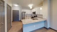 Located at 101 Three Mile Loop in Kannapolis, NC, this single-floor residence combines modern design with functional living spaces throughout. The open-concept kitchen serves as a central highlight, featuring crisp white shaker cabinetry, granite countertops, a classic subway tile backsplash, stainless steel appliances, and a peninsula with pendant lighting and an integrated sink — ideal for both meal preparation and casual dining. Wood-look flooring runs through the main living and kitchen areas, lending warmth and cohesion to the space. The living room is generously proportioned, finished with a ceiling fan and glass French doors that open to a private outdoor area, allowing natural light to fill the room. Multiple bedrooms are carpeted for comfort, each equipped with ceiling fans and windows fitted with blinds that provide ample natural light and outdoor views. A double-door closet offers notable storage capacity in one of the bedrooms. The bathrooms are well-appointed with granite vanity countertops, white cabinetry, and light wood-look flooring. One bathroom features a double-sink vanity, while another includes a full tub-shower combination. Neutral gray tones and dark baseboards are carried consistently throughout, creating a clean, cohesive aesthetic across the entire residence.