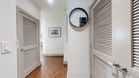This single-floor residence offers a well-designed layout encompassing two bedrooms, two bathrooms, and two closets across a comfortable footprint. The interior features rich hardwood-style flooring that flows through the main living areas, complemented by clean white walls and recessed lighting. The kitchen is a standout feature, boasting an expansive granite-topped island with bar seating, dark espresso cabinetry extending to the ceiling, a full suite of stainless steel appliances, a tile backsplash, and a double-basin sink — all illuminated by recessed ceiling lights. The kitchen opens directly to the dining and living areas, creating a seamless, social layout. The dining area is bathed in natural light from multiple large windows fitted with horizontal blinds, offering views of the surrounding greenery. Both bedrooms are carpeted and feature large windows with exterior views, providing a bright and restful atmosphere, and are each accompanied by a closet. The bathrooms are finished with large-format tile flooring, granite-topped dark vanities, and tub-shower combinations. A hallway connects the living spaces, accented by louvered doors and modern décor details, tying together the cohesive and contemporary design of the home.