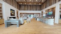 Located at 3220 Hatchet Bay Dr in Charleston, SC, this single-floor clubhouse delivers a striking fusion of rustic farmhouse character and refined coastal style. The space is defined by soaring ceilings clad in weathered reclaimed wood planks, paired with exposed timber beam details that establish a warm, barn-inspired atmosphere throughout.

Wide-plank light oak hardwood flooring flows seamlessly across the expansive open floor plan, connecting multiple distinct gathering zones. A central bar and lounge area features reclaimed wood countertops atop white paneled bases, surrounded by wishbone-style barstools, a textured 3D tile accent wall, wall-mounted television, and a bold linear pendant light fixture. Built-in shelving and a dedicated coffee station add everyday functionality to this social hub.

The main lounge area offers generous seating arrangements including plush sofas, upholstered armchairs, and a large octagonal marble-top coffee table, anchored by a white brick fireplace with custom built-in shelving. Decorative cross-timber wall panels serve as architectural focal points throughout.

A secondary gathering zone features tufted banquette seating paired with white café tables, illuminated by dramatic swing-arm pendant lights against a white brick wall. Tall windows and glass double doors flood this area with natural light and provide views of the surrounding landscape, reinforcing the space's bright, welcoming ambiance.
