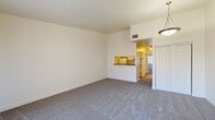 This single-floor, 2-bedroom, 1-bathroom residence offers a well-organized layout designed for comfortable everyday living. The open living room features neutral-toned carpet, clean white walls, and a pass-through window that connects directly to the kitchen, creating an open sightline between the two spaces. A pendant light fixture accents the entry area near the front door.

The galley-style kitchen is efficiently designed with ample white cabinetry both above and below the countertops, dark laminate countertops, a stainless steel sink, a dishwasher, a white refrigerator, and a white electric range. Light hardwood-style flooring runs throughout the kitchen, adding warmth to the space.

Both bedrooms are carpeted and bathed in natural light through windows dressed with vertical blinds. The primary bedroom includes a sliding double-panel closet, while the second bedroom features a walk-in closet with built-in shelving and a hanging rod, offering generous storage capacity.

The bathroom includes a white vanity with dark countertop, a mirror, and a combined tub-shower with tile surround. Hardwood-style flooring continues into the bathroom, tying the space together cohesively.

Overall, this residence presents a clean, practical, and well-maintained interior with a neutral palette throughout.