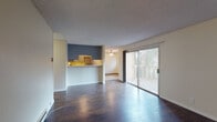 Located at 90 Lund Ave in Hayward, California, this single-floor residence offers a well-organized layout with a blend of functional design and comfortable living spaces. The open-concept living and dining area is finished with rich, dark hardwood flooring and features textured ceilings, baseboard heating, and a sliding glass door that leads to a private balcony overlooking lush greenery — filling the space with natural light and outdoor views. A ceiling fan adds comfort to the adjoining area, which flows seamlessly toward the rest of the unit. The kitchen is designed for efficiency, featuring gray cabinetry, stainless steel appliances including a range and refrigerator, a built-in dishwasher, a single-basin sink, and tile flooring — all framed by a raised breakfast bar pass-through that connects to the living area. The bedrooms are carpeted and well-lit by windows with views of the surrounding neighborhood, and each offers a calm, neutral palette. The bathroom is clean and functional, with a wide vanity, light stone countertop, large mirror, and a separate bathtub and shower area alongside wood-look flooring. A walk-in closet adjacent to the bathroom provides generous storage. Overall, the space presents a practical and inviting layout suited for comfortable everyday living.