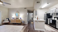 Located in Universal City, Texas, this single-story residence offers a thoughtfully designed layout with 1 bedroom, 2 full bathrooms, and a comfortable, efficient use of space throughout. The open-concept living and dining area immediately impresses with its vaulted ceilings, warm neutral tones, and durable wood-style flooring that carries throughout the home. Large windows in the living room invite abundant natural light and are complemented by a ceiling fan, creating a bright and airy atmosphere. A patio door provides direct access to the outdoor space. The kitchen is well-equipped with gray shaker-style cabinetry, white quartz countertops, stainless steel appliances, a black refrigerator, and a peninsula with a sink that opens toward the dining area. The spacious primary bedroom features vaulted ceilings, a ceiling fan, a natural light-filled window, and access to multiple closets, including a walk-in. Both bathrooms are finished with gray vanity cabinetry, white quartz countertops, and tub-shower combinations. A dedicated in-unit laundry area houses a full-size washer and dryer. Three closets throughout the home provide ample storage, rounding out this clean, modern, and highly functional residence.