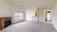 This well-laid-out 2-bedroom, 2-bathroom single-floor residence offers a comfortable and functional living experience. The open-concept living, dining, and kitchen area serves as the heart of the home, featuring soaring vaulted ceilings that enhance the sense of space and airiness. A wood-trimmed fireplace anchors the living room, adding warmth and character, while a ceiling fan provides year-round comfort. Large windows bathe the area in natural light and offer views of mature surrounding trees, with access to an outdoor balcony.

The kitchen is outfitted with warm wood cabinetry, a full suite of appliances including a stove, microwave, and refrigerator, and hardwood flooring that extends through the main living areas. A pass-through counter connects the kitchen to the dining and living spaces for a seamless layout.

The spacious primary bedroom features vaulted ceilings, multiple windows with outdoor views, a ceiling fan, and plush carpeting. Both bedrooms are served by closets with built-in wire shelving for organized storage. The two bathrooms are functional and clean, each featuring a shower-tub combination, warm wood vanity cabinetry, and hardwood flooring. Throughout the home, neutral tones and plush carpeting in the bedrooms create a calm, cohesive atmosphere.