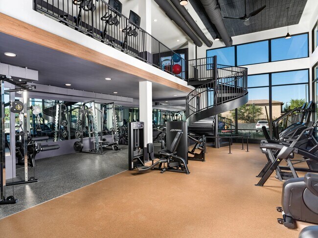 A spacious two-level fitness center at Modera Higley Commons, featuring expansive windows, advanced equipment, and room to train at your own pace. - Modera Higley Commons