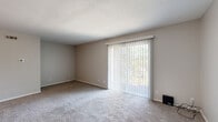 Located at 6516 N University St in Peoria, IL, this single-floor unit offers a well-organized layout with a clean, neutral aesthetic throughout. The kitchen is outfitted with rich dark cabinetry, light countertops, a stainless steel refrigerator, and a range, all set atop durable wood-look vinyl flooring that flows seamlessly into the main living areas. The open living and dining area is bright and versatile, with easy access to the kitchen and a textured ceiling that adds subtle character overhead. A standout feature is the sliding glass door found in one of the main rooms, fitted with vertical blinds and opening to a balcony with views of surrounding greenery, allowing natural light to fill the space. The bedrooms are finished with soft, neutral-toned carpet for added comfort, and each room benefits from natural light through windows dressed with blinds. One bedroom includes an open walk-in closet area, providing convenient storage. The bathroom is clean and functional, featuring a full tub-shower surround, toilet, and dark vanity set on wood-look flooring. Throughout the unit, white trim, neutral wall tones, and consistent flooring choices create a cohesive and move-in-ready environment.