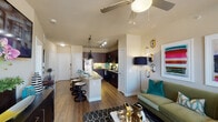 This single-floor residence offers a thoughtfully designed open-concept layout that seamlessly connects the living, dining, and kitchen areas. Rich wood-look flooring flows throughout the main living spaces, complemented by neutral warm-toned walls that create a welcoming ambiance. Ceiling fans are featured in both the living room and bedroom, enhancing comfort throughout.

The kitchen is a standout feature, showcasing dark espresso cabinetry that extends to the ceiling for ample storage, granite countertops, a classic white subway tile backsplash, and a full suite of appliances including a stainless steel refrigerator and black range and microwave. A central island with granite counters and bar seating provides additional prep space and casual dining.

The living area is bright and inviting, with large windows allowing natural light to fill the room and offering views to the outside. The bedroom continues the warm aesthetic with plush carpeting, generous window placement for natural light, and a ceiling fan overhead.

The bathroom is well-appointed with dark cabinetry, granite countertops, a framed mirror, and a tub-shower combination with white tile surround. The cohesive design palette of dark wood tones, granite surfaces, and warm neutrals gives this residence a polished and contemporary feel throughout.