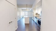 Located at 10045 111 St NW in Edmonton's vibrant Oliver neighbourhood, this well-designed one-bedroom, one-bathroom unit offers a thoughtful layout across a single floor. The kitchen is a standout feature, showcasing white cabinetry, quartz countertops, a subway tile backsplash, and a full suite of stainless steel appliances including a refrigerator, electric range, built-in microwave, and dishwasher. A central island with a quartz surface provides additional workspace and casual dining potential, while stylish pendant lighting adds a modern touch overhead. Dark hardwood-style flooring runs throughout the main living and kitchen areas, creating a warm contrast to the bright, white finishes. The bedroom offers a calm, neutral palette with light wood-tone flooring, and a large window frames views of the Edmonton skyline, allowing ample natural light. A dedicated closet provides practical storage. The bathroom is finished in a clean, contemporary style with a wide vanity, undermount sink, quartz countertop, white cabinetry, and a combined tub and shower enclosure with a curved rod. Neutral tile flooring ties the space together seamlessly. The overall ambiance is modern and functional, ideal for urban living.