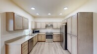 Located at 13809 E Carlisle Ave in Spokane Valley, WA, this single-floor unit offers a clean, contemporary design with a neutral color palette and light-toned luxury vinyl plank flooring throughout the main areas. The expansive kitchen is a standout feature, showcasing light wood cabinetry extending to the ceiling, generous counter space with light quartz countertops, recessed lighting, and a full suite of stainless steel appliances including a range, refrigerator, dishwasher, and microwave. A double-basin sink is positioned beneath a window, offering views of the surrounding greenery. The open layout visible from the dollhouse view connects the kitchen to a spacious living area, providing a comfortable flow throughout the unit. Bedrooms are finished with patterned carpet and feature walk-in closet space, as well as multiple windows that invite natural light and outdoor views. A dedicated laundry closet with a washer is conveniently tucked within the unit. The bathroom is clean and functional, featuring a full soaking tub and shower combination with light vinyl plank flooring. A wall-mounted mini-split unit provides climate control. Overall, the space presents a bright, well-appointed interior suited for comfortable everyday living.