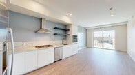 Located at 10375 Washington Blvd in the heart of Culver City, this modern one-bedroom, one-bathroom residence offers a thoughtfully designed open-concept layout with contemporary finishes throughout. Light wood-tone flooring flows seamlessly across the entire space, creating a warm and cohesive aesthetic.

The combined kitchen and living area serves as the heart of the residence. The kitchen is outfitted with sleek white cabinetry, a marble-veined quartz countertop and backsplash, stainless steel appliances including a gas cooktop, wall oven, dishwasher, and refrigerator, plus a stainless range hood and open floating shelves. The adjacent living area is bright and airy, with recessed lighting and a full-height sliding glass door that opens to outdoor views of the surrounding cityscape.

The bedroom is a well-proportioned retreat featuring a tray ceiling with integrated ambient lighting, a large window framing open city views, and a dedicated closet. The bathroom is finished with large-format tile, a glass-enclosed walk-in shower, a white vanity with a dark countertop, and a wide mirror. A hallway connects the main rooms, completing the efficient and functional floor plan.