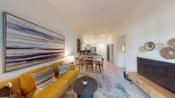 This single-floor residence is designed with a clean, contemporary aesthetic and an open-concept floor plan that connects the living, dining, and kitchen areas into one cohesive space. Light wood-style flooring runs throughout, complementing the bright white walls and elevated ceilings that lend a sense of openness and airiness.

The kitchen is a standout feature, outfitted with flat-front white cabinetry extending to the ceiling, dark stone countertops, a dark tile backsplash, and a full suite of stainless steel appliances including a range, microwave, dishwasher, and French door refrigerator. A peninsula with bar seating and pendant lighting overhead adds both functionality and style, flowing naturally into the dining area.

The living room is generously proportioned, featuring a sliding glass door that opens to a private balcony with outdoor views, allowing abundant natural light to fill the space. The bedroom is well-sized with a window overlooking greenery and direct access to a sleek en-suite bathroom. The bathroom features a backlit vanity mirror, floating white vanity, and a glass-enclosed walk-in shower with white tile surround—all finished to a high standard.