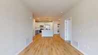 This contemporary 960 square foot apartment offers a blend of style and functionality. The heart of the home is an open-concept living area, seamlessly connecting the kitchen and living room. The kitchen is a highlight, boasting white cabinetry, stainless steel appliances, and a generous island with a sink, perfect for food preparation or casual dining.

Natural light floods the space through large windows, enhancing the warm tones of the hardwood flooring throughout the main living areas. The primary bedroom, measuring 330 square feet, provides ample space and features plush carpeting for comfort. A second bedroom offers versatility as a guest room or home office.

The bathroom is modern and pristine, with clean lines and contrasting black fixtures. In-unit laundry adds convenience to daily life. An attached single-car garage offers secure parking and additional storage space.

The apartment's neutral color palette and clean design create a canvas for personal style. With its thoughtful layout and contemporary finishes, this apartment combines comfort and efficiency in a compact yet well-designed space.