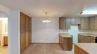 Located at 1617 Live Oak in Vista, this single-floor unit offers a well-organized layout designed for comfortable everyday living. The open-concept kitchen is a functional centerpiece, featuring an abundance of warm wood-toned cabinetry, generous counter space, a built-in range, a dishwasher, and a peninsula that connects seamlessly to the dining area. A pendant chandelier illuminates the dining space, which is further complemented by a tall storage cabinet wall, adding to the unit's overall storage capacity. The living room is generously sized, finished with plush carpeting, a textured ceiling, and a charming arched doorway that leads to the private quarters. Natural light filters in through vertical blinds in the bedroom areas, enhancing the bright and airy feel throughout. The bedrooms are well-proportioned with neutral carpet and clean walls, offering a calm and versatile space. Two full bathrooms serve the unit, each equipped with a tub-shower combination, chrome fixtures, tile flooring, and vanity storage. The overall palette is light and neutral, creating a clean, move-in-ready environment throughout the entire single-level floor plan.
