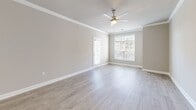 Located at 1411 Parkview Cir in Wilmington, NC, this 2-bedroom, 2-bathroom residence offers a thoughtfully designed single-floor layout with clean, modern finishes throughout. The open-concept kitchen and living area serves as the heart of the home, featuring light hardwood-style flooring, crown molding, and a ceiling fan. The kitchen is outfitted with crisp white shaker cabinetry, brushed nickel hardware, a white quartz island, subway tile backsplash, and a full suite of stainless steel appliances including a range, microwave, dishwasher, and refrigerator. A door from the living area leads directly to a private balcony, while large windows bathe the space in natural light. Both bedrooms are carpeted and equipped with ceiling fans; the primary bedroom offers generous proportions and direct access to its own bathroom. Three closets, including a walk-in with wire shelving, provide ample storage. The two bathrooms each feature tub-shower combinations with white subway tile surrounds and brushed nickel fixtures. Additional conveniences include a dedicated laundry area and a utility room, rounding out a complete and functional living space.