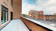 Located at 936 N High St in Columbus, Ohio, this single-floor space sits within the vibrant Short North Arts District, one of the city's most dynamic urban corridors. The property's most notable exterior feature is a spacious open-air terrace finished with large-format porcelain tile pavers and enclosed by a classic brick parapet wall. From the terrace, unobstructed views stretch across the surrounding rooftops to the neighborhood's characteristic red-brick mid-rise buildings, offering a compelling urban panorama beneath an open sky. The interior spaces, while dimly lit in their current state, reveal a layout defined by clean wall planes, doorway openings, and subtle architectural detailing. Ambient accent lighting at floor level hints at design-forward finishing touches throughout the interior. The overall construction reflects the area's industrial-influenced aesthetic, with exposed brick forming a consistent visual thread between the exterior terrace and the building envelope. This space benefits from its prime High Street address, placing it at the center of Columbus's most walkable and commercially active neighborhood, ideal for a variety of professional or retail uses.