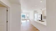 Located on the sixth floor at 517 67 Ave SW in Calgary, this two-bedroom, two-bathroom unit offers a well-designed open-concept layout with clean, contemporary finishes throughout. Light hardwood flooring runs continuously through the space, complementing the crisp white walls and recessed lighting that keep the interior bright and airy.

The kitchen is a standout feature, equipped with stainless steel appliances including a refrigerator and range, white flat-panel cabinetry, a subway tile backsplash, and a generous island with an undermount sink — ideal for both cooking and casual dining. The open sightlines from the kitchen connect seamlessly to the adjacent living areas.

Both bathrooms are finished in a clean, minimal style, each featuring a full soaker tub and shower combination, white surrounds, light wood flooring, and ample vanity storage. The primary bedroom is a comfortable size, featuring large windows that frame sweeping views of the Calgary skyline and surrounding neighbourhood, filling the room with natural light.

A dedicated closet and hallway provide practical storage solutions. The building's exterior balcony offers open views across the modern multi-storey complex, with the surrounding urban landscape of Southwest Calgary visible in the distance, rounding out a polished and functional urban residence.