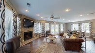 Located at 2181 Dunlap St in North Charleston, SC, this well-appointed single-story home showcases an open-concept floor plan that seamlessly connects the living, dining, and kitchen areas. Rich hardwood flooring runs throughout, anchoring the warm and cohesive design.

The spacious living room is a standout, centered around a striking floor-to-ceiling stone fireplace with a mounted flat-screen TV above. Large windows dressed with bold patterned drapes flood the room with natural light, while a ceiling fan with recessed lighting adds comfort and style. A set of French doors provides easy access to the outdoors. An accent wall featuring a bold geometric wallpaper treatment adds a contemporary design element to the space.

The open dining area accommodates a substantial wooden dining table with ample seating, positioned beside large windows that continue the theme of natural light. It flows directly into the kitchen, which features granite countertops, white cabinetry, stainless steel appliances including a refrigerator and range, a peninsula with bar seating, and pendant lighting overhead.

The kitchen is well-equipped and efficiently laid out, with additional prep space and a sink along the perimeter. Throughout the home, the neutral gray wall tones, coordinated textiles, and thoughtful décor create a cohesive, inviting ambiance suitable for both everyday living and entertaining.
