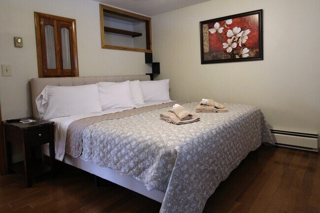 Dormitorio con cama king size y suelos de madera noble. - 2820 NY-28