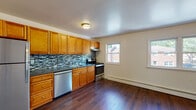 Located at 510 Maloney in Poughkeepsie, NY, this 2-bedroom, 1-bathroom unit is laid out on a single floor and offers a clean, functional living environment. The kitchen is a standout feature, showcasing warm honey-toned cabinetry, dark granite-style countertops, a stylish mosaic tile backsplash, and stainless steel appliances including a dishwasher, range, and refrigerator. Rich, dark hardwood-style flooring extends throughout the kitchen and living areas, adding warmth and continuity to the space. Natural light filters in through multiple windows, brightening the open kitchen and dining area. The living room features a ceiling fan and hardwood-style floors, with a convenient passage connecting to the rest of the unit. Both bedrooms are carpeted for comfort and feature neutral walls, ample natural light from large windows with outdoor views, and generous closet space — one bedroom includes a double closet setup. The full bathroom is neatly appointed with a shower-tub combination, a white vanity with sink, and tile flooring. Throughout the unit, the clean, neutral palette and practical finishes create a welcoming and move-in-ready atmosphere.