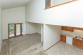 Located at 7492 26 Mile Rd in Shelby Township, Michigan, this two-story home offers a functional and straightforward layout across both levels. The main living area is notably spacious, featuring soaring vaulted ceilings that lend an open, airy feel to the space. Natural light enters through a entry door with sidelights, and neutral carpet flows throughout the living areas. A chandelier and wall-mounted light fixtures provide warm ambient lighting.

A staircase with warm wood railings and banisters connects the two floors, leading to an upper-level hallway that overlooks the main living space below. The upper level includes carpeted bedrooms, each equipped with closet space and wood-trimmed doorways.

The kitchen is well-appointed with solid oak cabinetry, ample counter space, and tile flooring. It includes a black range, white refrigerator, dishwasher, and an under-cabinet range hood. Two bathrooms serve the home — one featuring a tub/shower combination with tile flooring and oak vanity cabinetry, and another with a walk-in glass-door shower stall and matching vanity. A dedicated utility room houses the water heater and washer/dryer hookups, adding to the home's practicality.