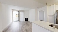 Located at 615 South Kenmore Avenue in the Koreatown neighborhood of Los Angeles, this single-floor residence offers three bedrooms and three bathrooms with a clean, modern aesthetic throughout. Light wood-style flooring runs continuously across the living areas and bedrooms, complementing the bright white walls and creating a cohesive, contemporary feel.

The open-concept living area is a standout feature, anchored by a fireplace and floor-to-ceiling sliding glass doors with vertical blinds that lead to a private balcony, allowing natural light to pour in. The kitchen is well-appointed with white shaker cabinetry, stainless steel appliances including a refrigerator, microwave, and gas range, a mosaic tile backsplash, and a generous quartz peninsula countertop with a double undermount sink—ideal for both cooking and casual dining.

Each of the three bedrooms offers a calm, neutral palette with wood-style flooring and natural light. The spacious primary bedroom includes its own dedicated closet space. Two walk-in or reach-in closets provide ample storage throughout the unit. The three bathrooms are finished in clean white tile, with tub-shower combinations offering a practical, classic design. The overall ambiance is bright, minimalist, and move-in ready.