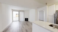 Located at 615 South Kenmore Avenue in the Koreatown neighborhood of Los Angeles, this single-floor residence offers three bedrooms and three bathrooms with a clean, modern aesthetic throughout. Light wood-style flooring runs continuously across the living areas and bedrooms, complementing the bright white walls and creating a cohesive, contemporary feel.

The open-concept living area is a standout feature, anchored by a fireplace and floor-to-ceiling sliding glass doors with vertical blinds that lead to a private balcony, allowing natural light to pour in. The kitchen is well-appointed with white shaker cabinetry, stainless steel appliances including a refrigerator, microwave, and gas range, a mosaic tile backsplash, and a generous quartz peninsula countertop with a double undermount sink—ideal for both cooking and casual dining.

Each of the three bedrooms offers a calm, neutral palette with wood-style flooring and natural light. The spacious primary bedroom includes its own dedicated closet space. Two walk-in or reach-in closets provide ample storage throughout the unit. The three bathrooms are finished in clean white tile, with tub-shower combinations offering a practical, classic design. The overall ambiance is bright, minimalist, and move-in ready.