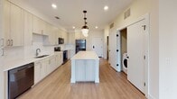Located at 3718 University Dr in Durham, NC, this single-floor residence showcases a clean, modern design with thoughtfully curated finishes throughout. The open-concept kitchen serves as a central highlight, featuring light wood-tone cabinetry extending to the ceiling, stainless steel appliances including a refrigerator, range, and microwave, and a generous white quartz island illuminated by striking globe pendant lights with matte black hardware. Light wood-tone flooring runs throughout the main living areas, creating a seamless, airy flow into the living space, which benefits from large windows and access to an outdoor area.

The bedrooms offer plush carpeting, ceiling fans, and dual windows that invite natural light and exterior views. The primary bathroom is notably spacious, presenting a long dual-sink vanity with granite countertops, light cabinetry, matte black fixtures, and direct access to a walk-in closet with wire shelving systems. A secondary bathroom features a tiled tub-shower combination with matte black fixtures. Additional storage closets and an in-unit washer hookup add everyday convenience. The overall aesthetic is bright, contemporary, and move-in ready.