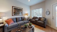 This single-floor residence presents a cohesive modern design characterized by a neutral color palette, light hardwood-style flooring, and recessed lighting throughout the main living areas. The kitchen is a standout feature, showcasing dark espresso cabinetry that extends to the upper walls, a light blue-green glass tile backsplash, stainless steel appliances including a refrigerator, range, microwave, and dishwasher, and a central island with granite countertops that doubles as a casual dining and prep space. Pendant lighting above the island adds a contemporary touch, while the open layout connects seamlessly to the living and dining areas.

The living room is a comfortable, well-lit space benefiting from natural light through large windows with blinds. It features the same warm hardwood-style flooring and offers a relaxed, functional layout. The bedrooms are carpeted for comfort, each receiving natural light and providing a calm, restful atmosphere. The bathroom is finished to a high standard, featuring large-format tile flooring, dark cabinetry with granite countertops, a vessel sink, brushed nickel fixtures, and a glass-enclosed walk-in shower, contributing to an overall sense of refined, contemporary living.