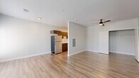 Located at 3680 Paramount Dr in West Lafayette, Indiana, this single-floor unit offers a well-designed layout that maximizes its compact footprint. The open-concept kitchen and living area serves as the heart of the space, featuring light hardwood-style flooring, neutral gray walls, and a ceiling fan that contributes to a bright, airy feel. A set of French doors with shuttered blinds fills the living area with natural light and provides outdoor access.

The galley-style kitchen is thoughtfully appointed with dark espresso cabinetry, sleek gold-toned hardware, light quartz countertops, and a classic white subway tile backsplash. Stainless steel appliances — including an electric range, built-in microwave, dishwasher, and refrigerator — complete the modern culinary setup. A stainless undermount sink and wall-mounted range hood add functional detail.

The bathroom features a soaking tub and shower combination enclosed by a sliding glass door, accented with elegant herringbone white tile. Matching hardwood-style flooring runs through this space as well, maintaining visual consistency. A stacked washer and dryer unit is conveniently integrated within the bathroom, offering practical in-unit laundry. An additional room provides flexible space with a window for natural light. The overall aesthetic is clean, modern, and efficiently designed.