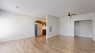 Located at 3680 Paramount Dr in West Lafayette, Indiana, this single-floor unit offers a well-designed layout that maximizes its compact footprint. The open-concept kitchen and living area serves as the heart of the space, featuring light hardwood-style flooring, neutral gray walls, and a ceiling fan that contributes to a bright, airy feel. A set of French doors with shuttered blinds fills the living area with natural light and provides outdoor access.

The galley-style kitchen is thoughtfully appointed with dark espresso cabinetry, sleek gold-toned hardware, light quartz countertops, and a classic white subway tile backsplash. Stainless steel appliances — including an electric range, built-in microwave, dishwasher, and refrigerator — complete the modern culinary setup. A stainless undermount sink and wall-mounted range hood add functional detail.

The bathroom features a soaking tub and shower combination enclosed by a sliding glass door, accented with elegant herringbone white tile. Matching hardwood-style flooring runs through this space as well, maintaining visual consistency. A stacked washer and dryer unit is conveniently integrated within the bathroom, offering practical in-unit laundry. An additional room provides flexible space with a window for natural light. The overall aesthetic is clean, modern, and efficiently designed.