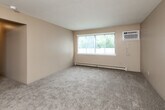 Located at 4108 Hubbell Ave in Des Moines, Iowa, this single-floor, two-bedroom, one-bathroom unit offers a practical and functional layout. The living room is generously proportioned with soft carpeting, neutral beige walls, a textured ceiling, a baseboard heating system, and a window unit air conditioner alongside a large window that invites natural light and outdoor views of surrounding greenery. The galley-style kitchen is efficiently designed, featuring warm oak cabinetry, a double-basin sink with laminate countertops, tile flooring, and white appliances including a range and dishwasher. Both bedrooms are carpeted and finished with neutral tones, offering a comfortable and quiet atmosphere. Each room is equipped with baseboard heating, and the primary bedroom includes a ceiling fan with a light fixture, a window with natural light, and a sliding-door closet for ample storage. The second bedroom similarly features a closet with warm wood-toned doors. Throughout the unit, rich wood-trimmed doorframes add a classic touch. The full bathroom includes a vanity with oak cabinetry, tile flooring, and a tub-shower combination. Three closets throughout the unit provide generous storage, and a hallway connects all living spaces cohesively.