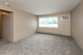 Located at 4108 Hubbell Ave in Des Moines, Iowa, this single-floor, two-bedroom, one-bathroom unit offers a practical and functional layout. The living room is generously proportioned with soft carpeting, neutral beige walls, a textured ceiling, a baseboard heating system, and a window unit air conditioner alongside a large window that invites natural light and outdoor views of surrounding greenery. The galley-style kitchen is efficiently designed, featuring warm oak cabinetry, a double-basin sink with laminate countertops, tile flooring, and white appliances including a range and dishwasher. Both bedrooms are carpeted and finished with neutral tones, offering a comfortable and quiet atmosphere. Each room is equipped with baseboard heating, and the primary bedroom includes a ceiling fan with a light fixture, a window with natural light, and a sliding-door closet for ample storage. The second bedroom similarly features a closet with warm wood-toned doors. Throughout the unit, rich wood-trimmed doorframes add a classic touch. The full bathroom includes a vanity with oak cabinetry, tile flooring, and a tub-shower combination. Three closets throughout the unit provide generous storage, and a hallway connects all living spaces cohesively.