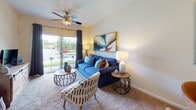 Located in Pooler, Georgia, this single-story residence at Alta Towne Lake offers a well-organized layout designed for comfortable everyday living. The living room serves as the central gathering space, featuring plush carpeting, a ceiling fan, and a sliding glass door that fills the room with natural light while providing direct access to an outdoor area with views of the surrounding greenery.

Adjacent to the living room, the dining area accommodates a full dining set and is defined by light tile flooring that transitions from the kitchen. A large decorative mirror enhances the sense of space within this area.

The galley-style kitchen is efficiently arranged with warm wood cabinetry lining both sides, offering generous storage. Black appliances, including an electric range and dishwasher, complement the tile backsplash and laminate countertops, while tile flooring ensures easy maintenance.

The primary bedroom features carpeting, a ceiling fan, and a window that draws in natural light. It connects to a well-appointed bathroom with rich wood cabinetry, a long vanity with ample counter space, tile flooring, and a closet with louvered doors. The second bedroom also includes carpeting, a ceiling fan, and a natural light-filled window, with its own private access to an adjacent space.
