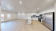 Located at Desert Color in Saint George, Utah, this well-appointed one-bedroom, one-bathroom unit offers a clean, contemporary design with a bright and efficient layout. The open-concept kitchen and living area serves as the heart of the home, featuring light hardwood-style flooring, recessed lighting, and crisp white walls that create an airy, welcoming ambiance. The kitchen is a standout, equipped with white shaker-style cabinetry, a grey tile backsplash, a full suite of stainless steel appliances including a refrigerator with ice maker, electric range, and microwave, as well as a peninsula island topped with striking white quartz countertops — ideal for both meal prep and casual dining. The living area flows seamlessly from the kitchen and includes access to a private balcony through a glass-panel door, bringing in natural light and outdoor views. The bedroom is a comfortable retreat with a tray ceiling, a ceiling fan with light, a window with exterior views, and direct access to a dedicated closet. The bathroom is finished with white shaker vanity cabinetry, a grey countertop, a framed mirror, and a shower-tub combination. Consistent hardwood-style flooring and neutral tones throughout tie the entire space together cohesively.