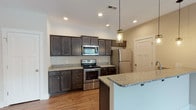 The Shenandoah is a thoughtfully designed 2-bedroom, 2-bathroom single-floor residence that combines modern finishes with comfortable, functional living. The open-concept layout connects the living area and kitchen seamlessly, with warm wood-look flooring running throughout the main living spaces. The living room features a sleek built-in fireplace and a ceiling fan, creating an inviting atmosphere for everyday living. The well-equipped kitchen is a standout feature, showcasing dark espresso-toned cabinetry, granite countertops, a full suite of stainless steel appliances including a range, microwave, refrigerator, and dishwasher, along with a peninsula that provides additional prep and dining space. Mason jar pendant lighting adds a charming touch overhead. Both bedrooms are carpeted for comfort and include ceiling fans, with the primary bedroom offering access to a spacious walk-in closet with wire shelving. The two bathrooms are finished with tile flooring; one features a soaking tub and the other a walk-in shower. Recessed lighting and neutral wall tones throughout the home create a clean, modern ambiance well-suited for a variety of décor styles.