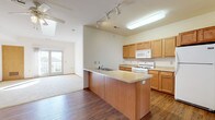 Located at 2707 Park Place Ln in Janesville, Wisconsin, this single-floor home offers a thoughtfully designed open-concept layout filled with natural light. The main living and kitchen area serves as the heart of the home, where warm hardwood-style flooring flows seamlessly throughout. The kitchen is well-appointed with honey-toned wood cabinetry, light countertops, a central island with a built-in sink, a gas range, microwave, and refrigerator. Track lighting and a skylight brighten the space, while a pendant light adds a subtle decorative touch. The living area extends naturally from the kitchen, featuring vaulted ceilings, a ceiling fan, and an additional skylight that enhances the airy feel. French doors provide access to an outdoor area, allowing natural light to pour in. The bedrooms offer plush carpeting, skylight features, and generous windows with neighborhood views. The bathrooms are finished with tile flooring, wood vanities with granite-style countertops, large mirrors, and walk-in shower options. A built-in shelving unit adds practical storage. The overall ambiance is clean, bright, and functional, making this a comfortable and inviting single-level home.