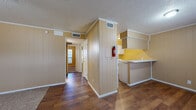 Located at 2502 Sweetbriar Dr in San Angelo, Texas, this single-story home offers a straightforward and functional layout throughout. The interior is characterized by warm-toned vertical wood paneling that runs consistently through the main living areas, hallways, and bedrooms, lending a cohesive, classic aesthetic. Textured ceilings and white crown molding frame each room, while ceiling fans provide comfort across the living and sleeping spaces.

The living area features a combination of hardwood-style flooring and carpet, transitioning naturally into the home's various rooms. A central hallway connects the main living space to the bedrooms, each of which is carpeted and equipped with a ceiling fan and window with blinds for natural light and ventilation. The bedrooms offer comfortable proportions with ample wall space.

The galley-style kitchen is efficiently arranged with white cabinetry, a double-basin stainless steel sink, white electric range, and light countertops — all set against wood-paneled walls with hardwood-style flooring underfoot. A pass-through counter connects the kitchen to the adjacent living area.

The bathroom includes a full tub-shower combination with white subway tile surround, standard fixtures, and overhead cabinetry for storage. This home provides a practical and livable layout well-suited for comfortable single-floor living in San Angelo.