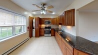 Cedar Manor Unit 1335B is a single-floor, one-bedroom, one-bathroom residence located in Cedar Grove, NJ. The layout connects a spacious living area to the kitchen via an open pass-through, creating a cohesive and functional flow throughout the unit.

The living area is finished with polished hardwood floors that reflect natural light streaming in through multiple windows. Crown molding and recessed lighting add a clean, refined character to the space. A wall-mounted HVAC unit and baseboard heating provide year-round climate control.

The kitchen is a standout feature, outfitted with rich, warm-toned wood cabinetry, dark granite countertops, a tiled backsplash, and stainless steel appliances including a gas range, microwave, and refrigerator. A ceiling fan overhead and a separate entrance door enhance both comfort and convenience. The flooring transitions to large-format ceramic tile in this area.

The bedroom is generously proportioned, featuring hardwood floors, recessed lighting, crown molding, multiple windows with outdoor views, and a dedicated closet for ample storage.

The bathroom is neatly finished with tile walls and flooring, a white vanity with a wide mirror, and a combined tub and shower. A window allows for natural light and ventilation, completing this well-maintained unit.